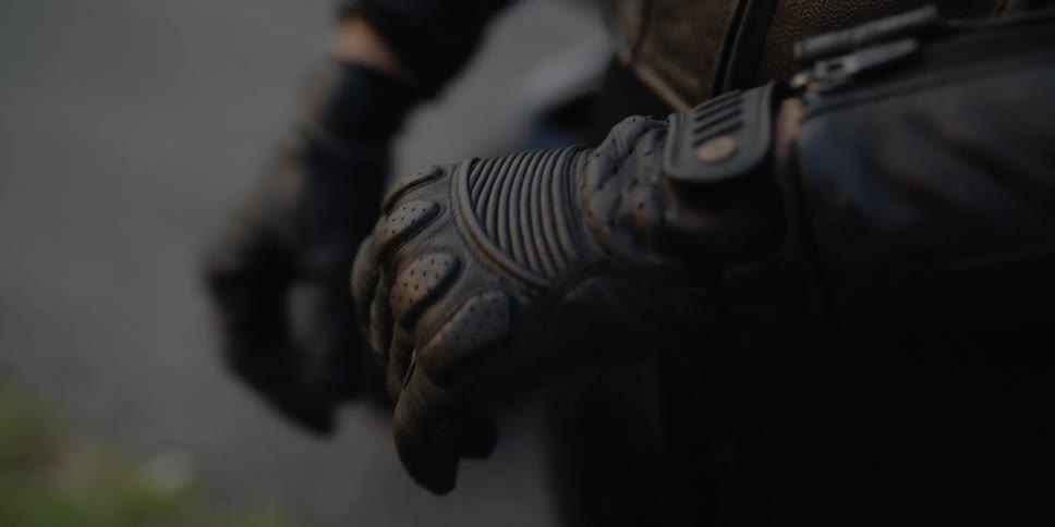 A motorcycle rider tightens the straps on his leather gloves