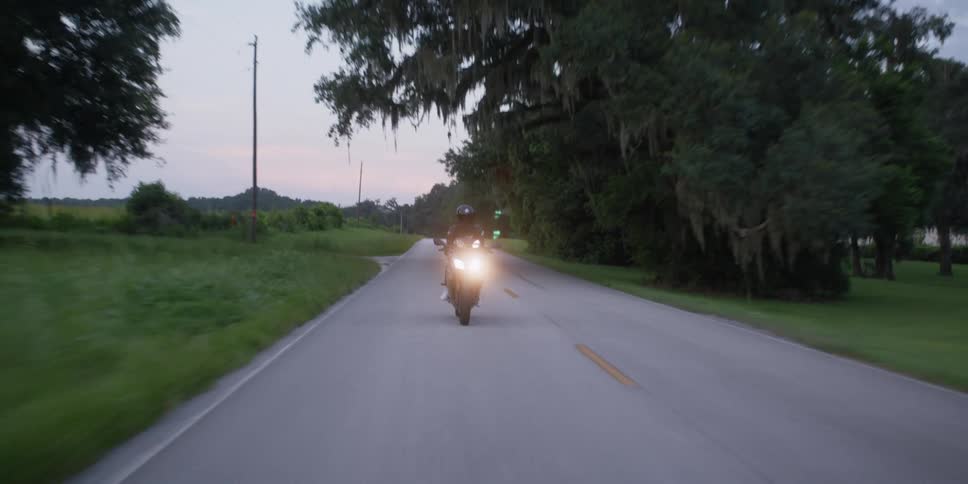 A person rides a motorcycle on a quiet rural road