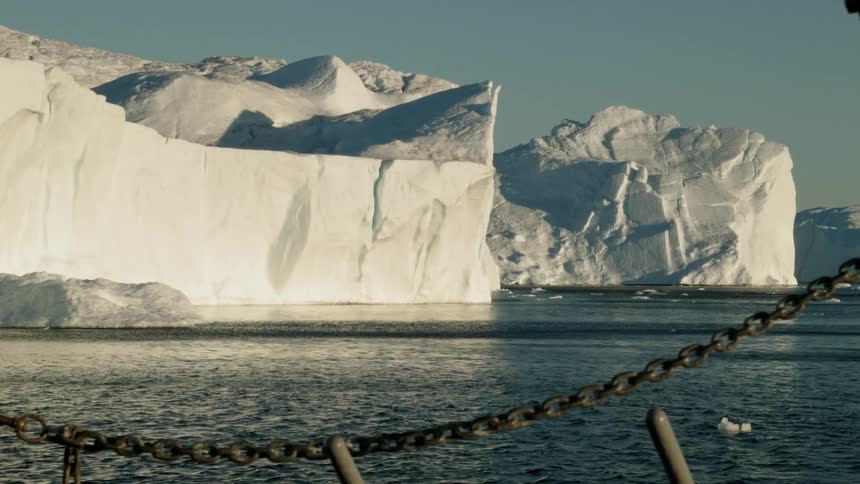 A boat floats down a  body of water next to two large glaciers