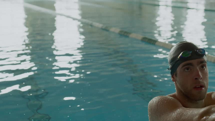 A swimmer rests at the edge of the pool