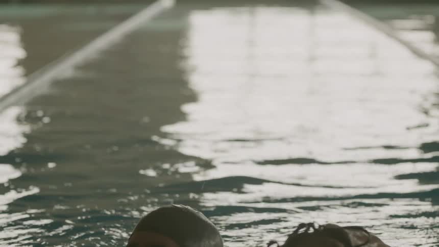 A swimmer in a pool celebrates and then gets out of the pool