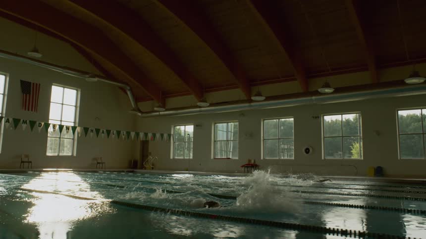 Swimmers pushing off the wall and racing in their lanes at an indoor pool