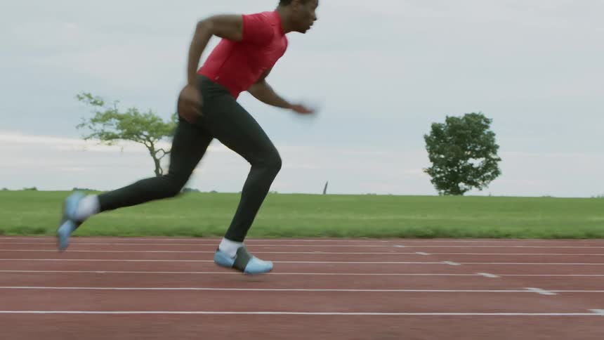 A man runs down a track on a cloudy day