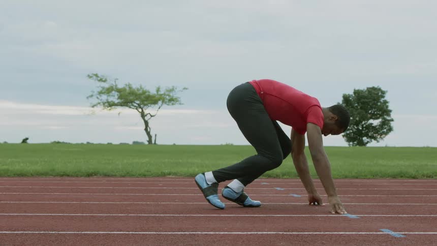 Man getting ready to sprint on a running track