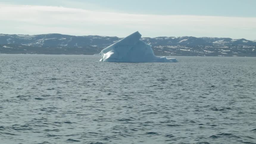 A large iceberg floats in the water ahead