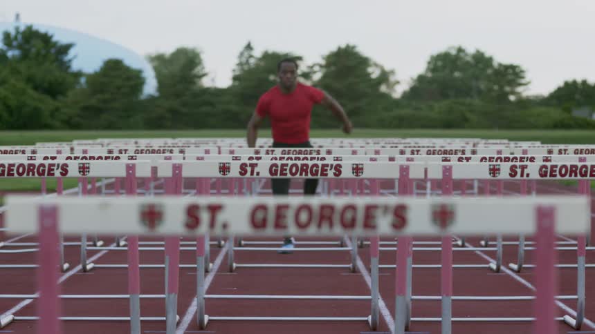 A man jumps the hurdles on an outdoor track