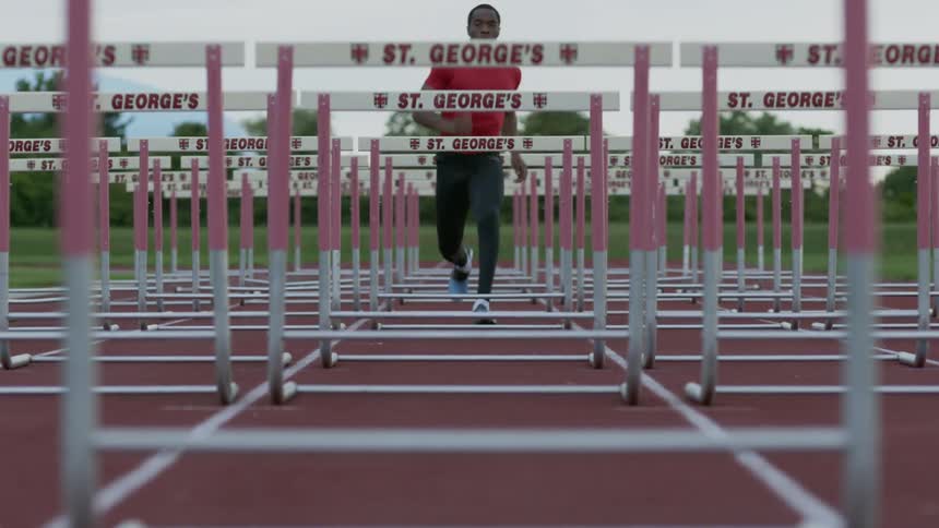 A man jumps a succession of hurdles on a track
