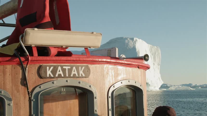 The nameplate of a boat that is passing a large glacier on a clear day