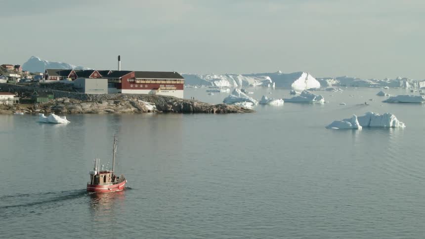 A red tug boat floats towards a chunk of ice