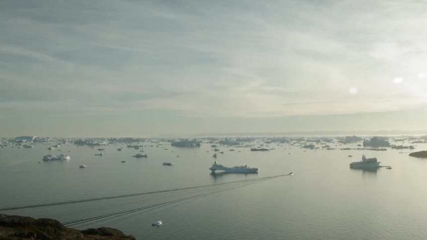 A boat goes out between the icebergs