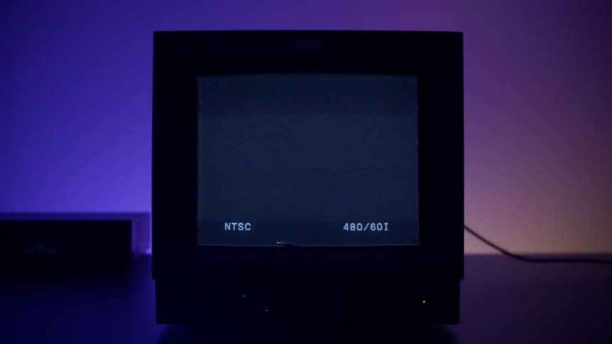 A television displays a paused tape with static while colorful lights glow behind it
