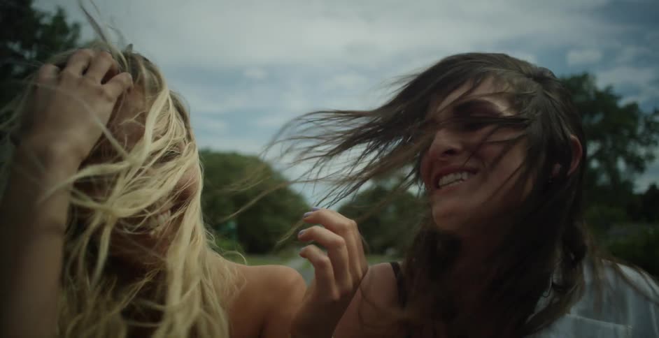Two women are riding in a car with wind blowing through their hair