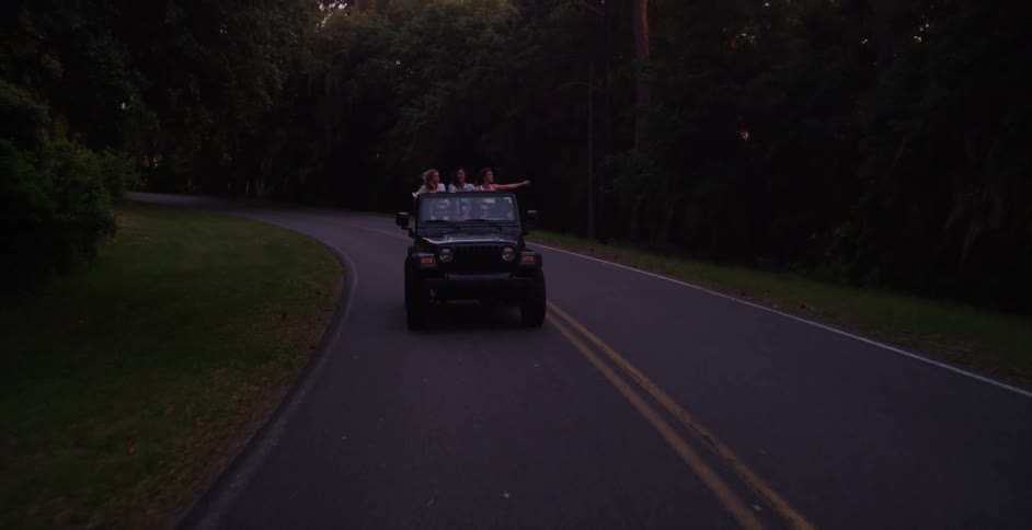 A car full of people is driving down a road at dawn