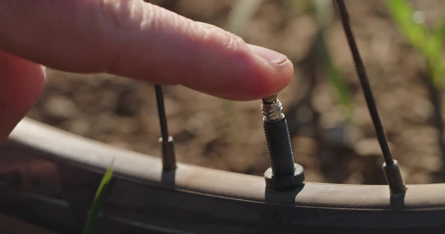 A person pressing their bicycle tire valve to release air