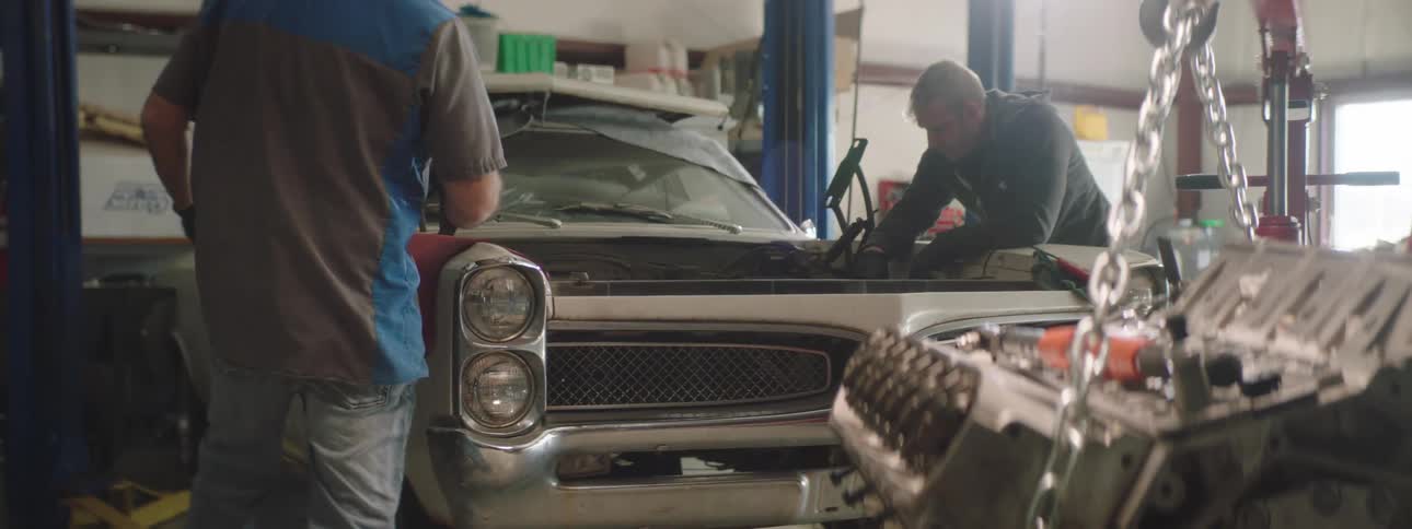 Two car mechanic repair the engine of a car at the garage