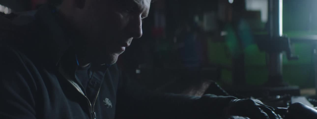 Car mechanic in a grey shirt and jacket works at the garage