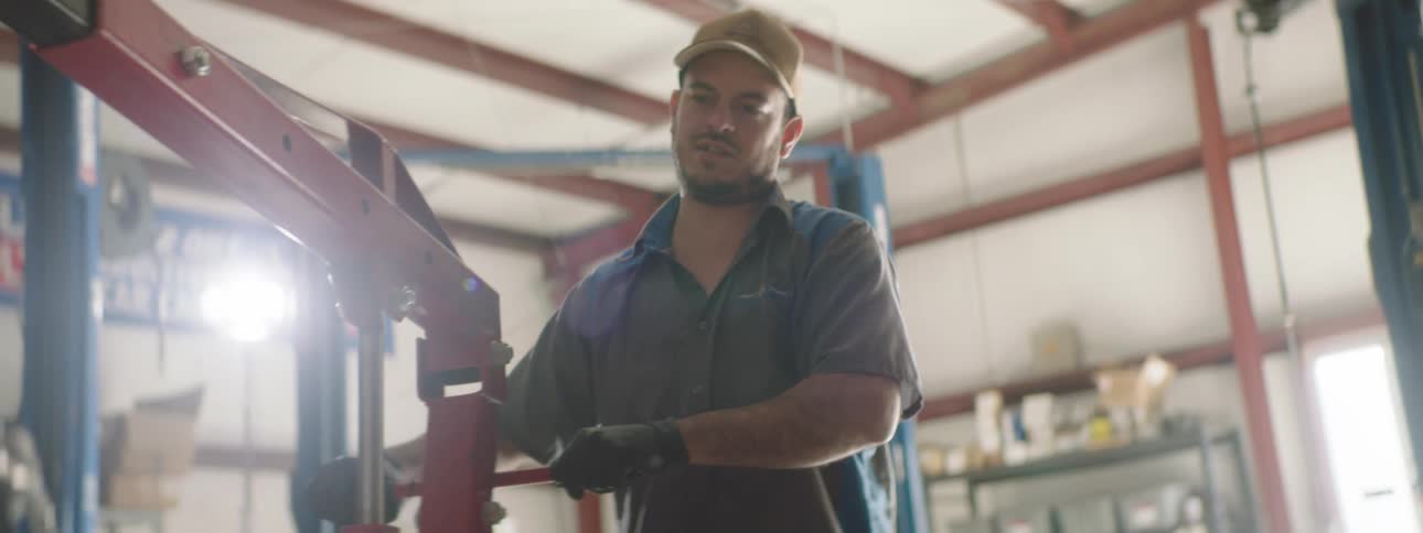A mechanic working in a shop moving an engine