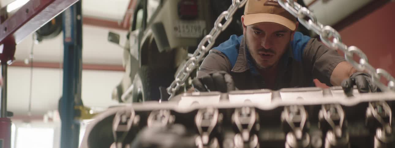 Two men work beside each other on an engine inside a commercial garage