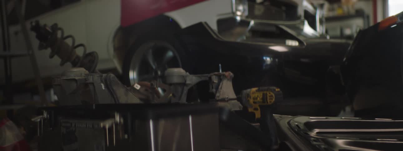 A garage with tools and a vehicle with a wall and window in the background