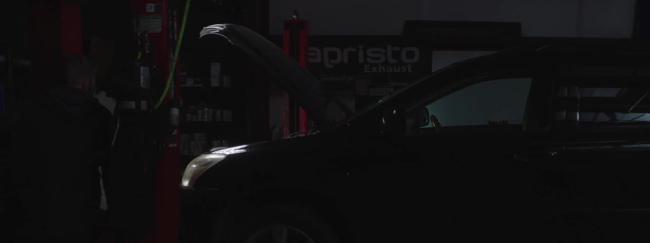 A man is working on a car in a garage at night