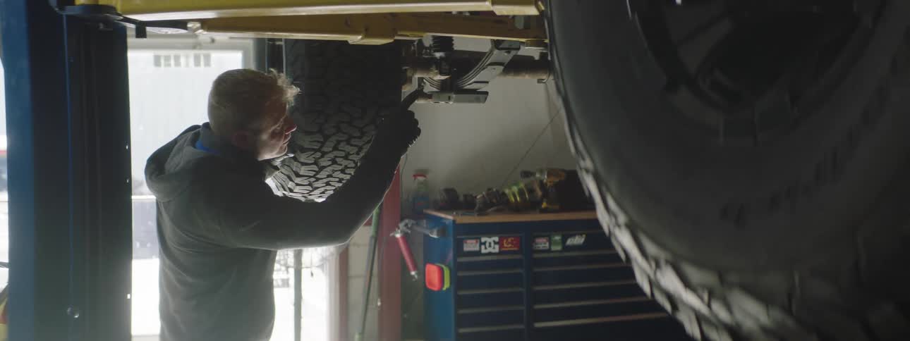 A man is working in a car shop during the day