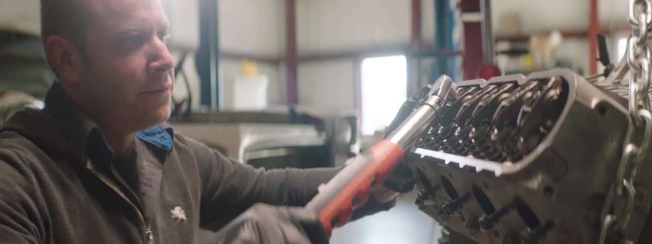 Man uses a tool to work on machinery in a workshop
