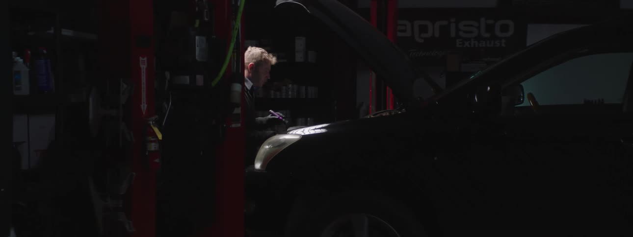 A man is working on a car in a garage at night