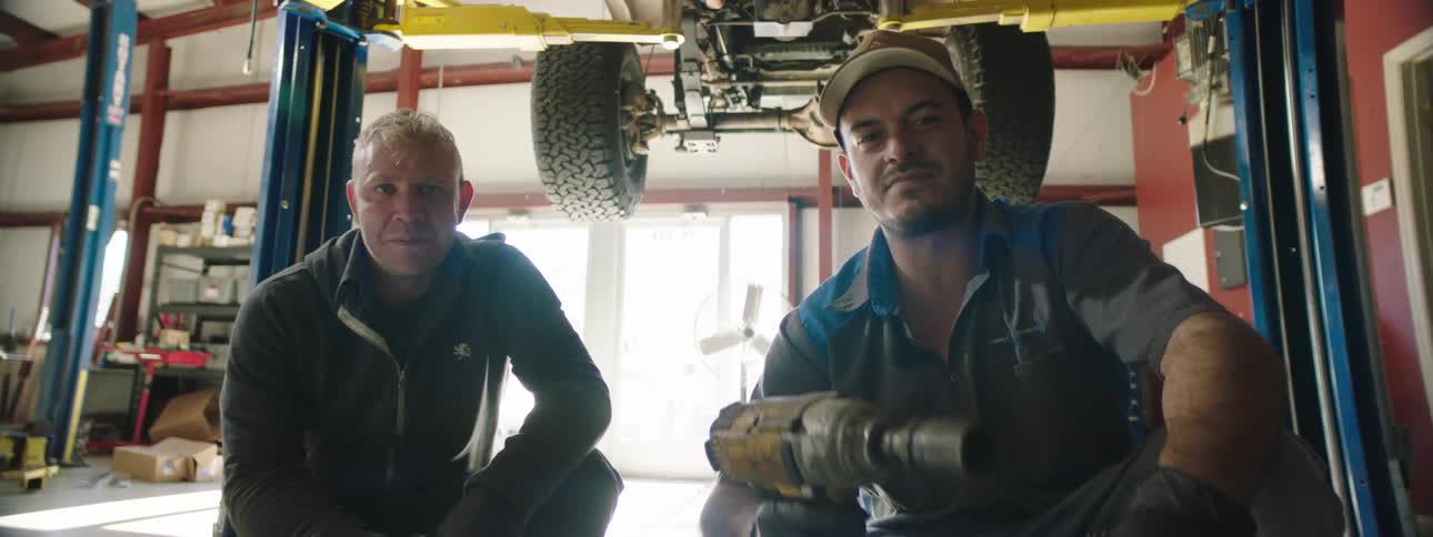 Two employees are in an automotive shop with tools