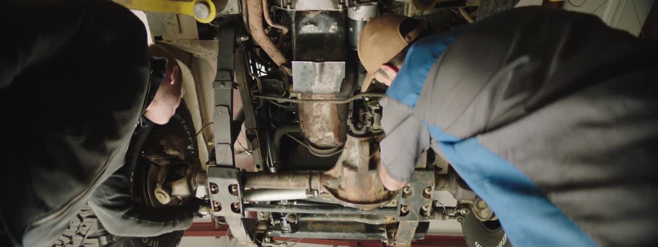 Two men are working on a car in an automotive shop