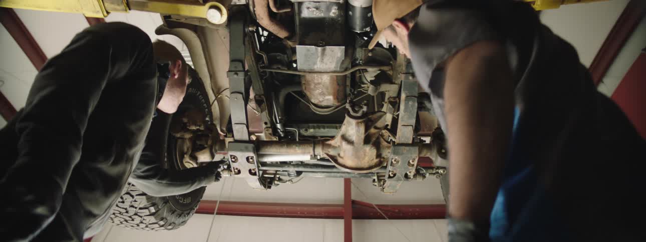Two mechanics are working on a car in a garage