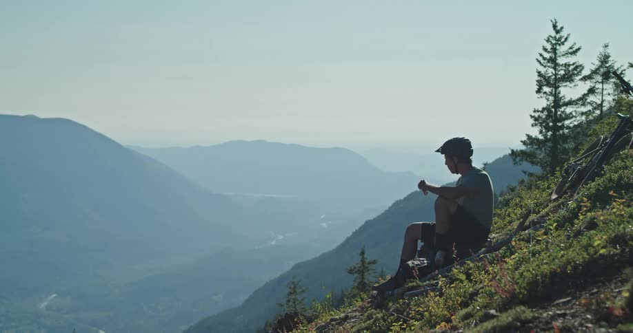 A mountain biker takes a break from climbing to eat a snack on an alpine mountain ridge