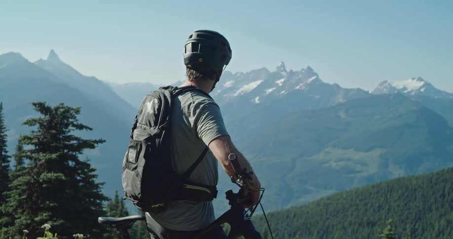 A man is looking at the view of the mountains on his bike