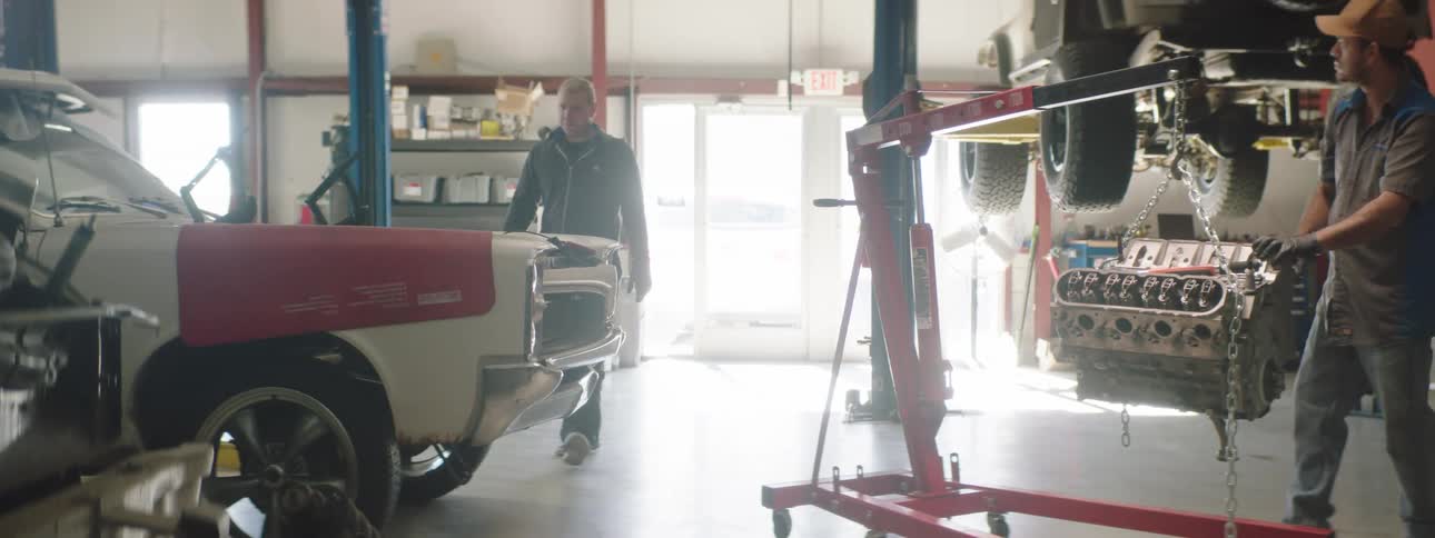 Two coworkers are working in an automotive shop together