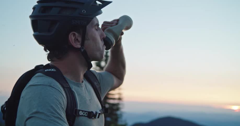 A man drinks out of his water bottle when he is resting during a bike ride