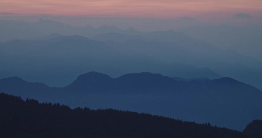 Distant mountain range layers sit in haze at dusk