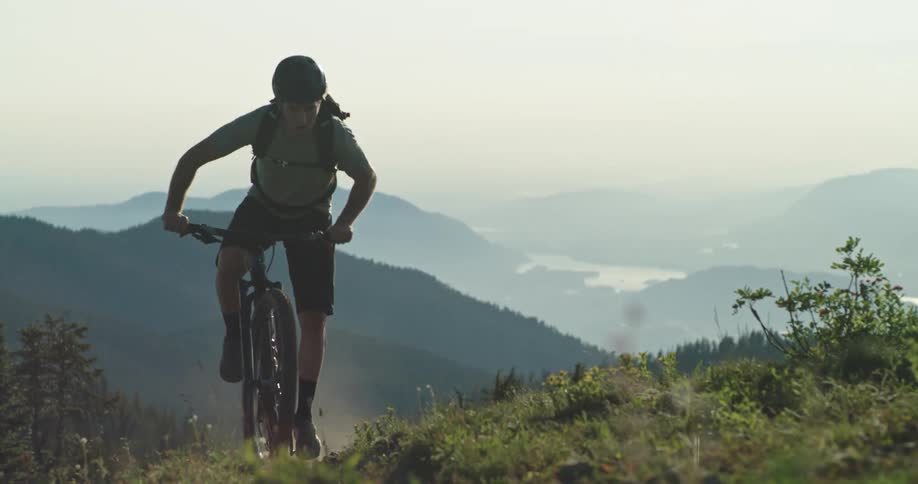 A man pedals his bike hard riding up the steep mountain trail