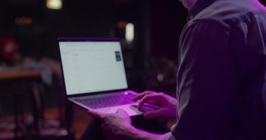 A man is sitting on a chair and browsing on a laptop