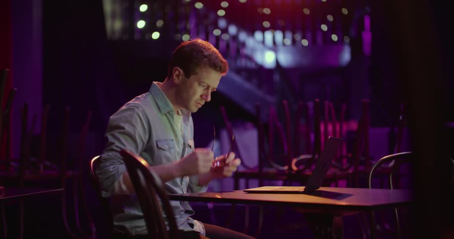 A man is sitting at a table and is on a laptop