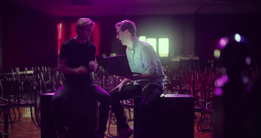 Two men are talking together in an empty venue
