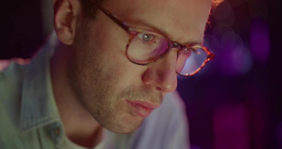 A man is sitting in a room and wearing glasses