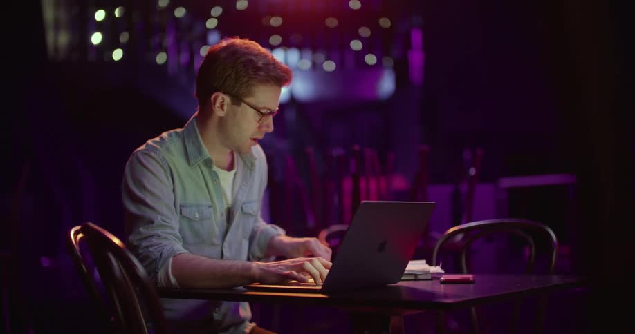 A man in a club working on a laptop