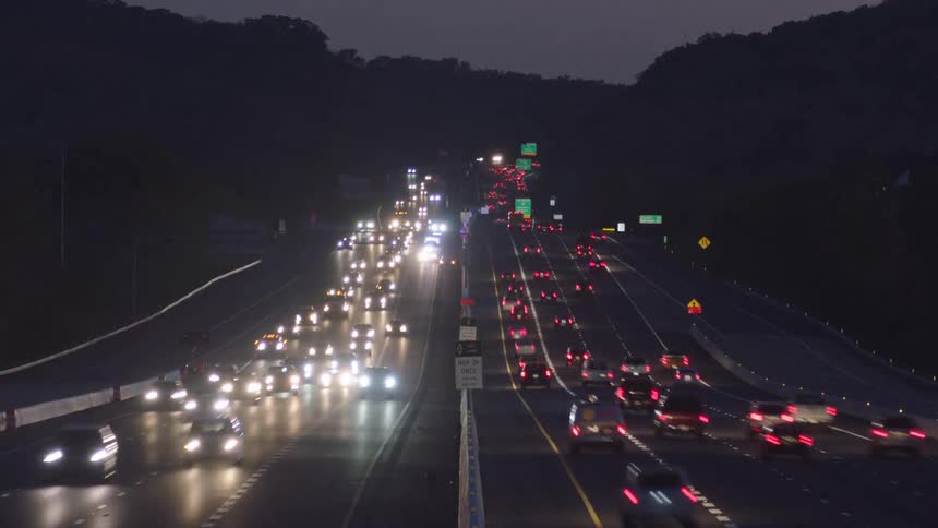 Traffic moves along busy divided highway at night