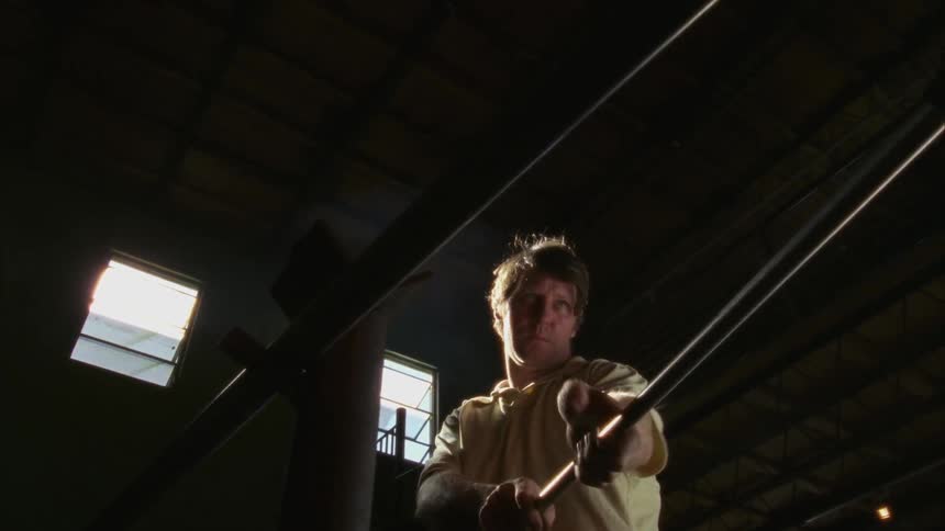 A glass worker crafts glass on a steel rod