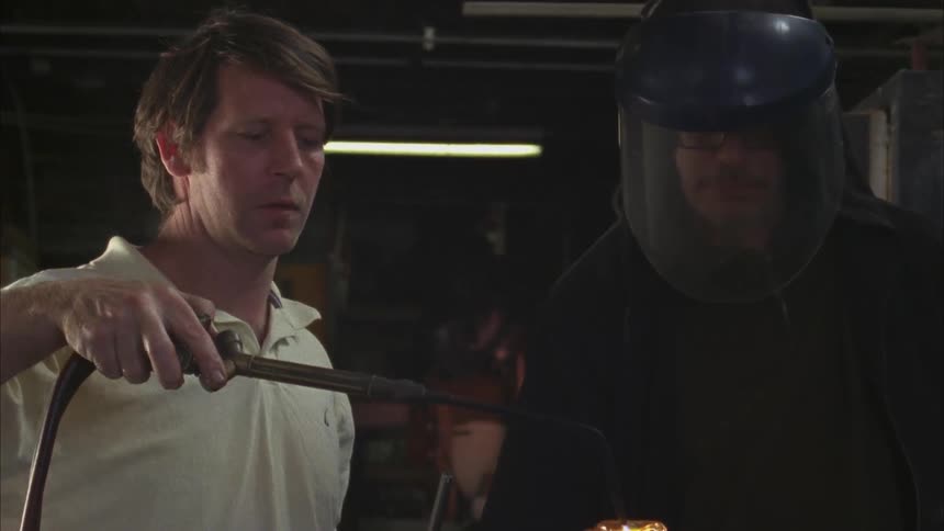 A man is using a torch to blow glass