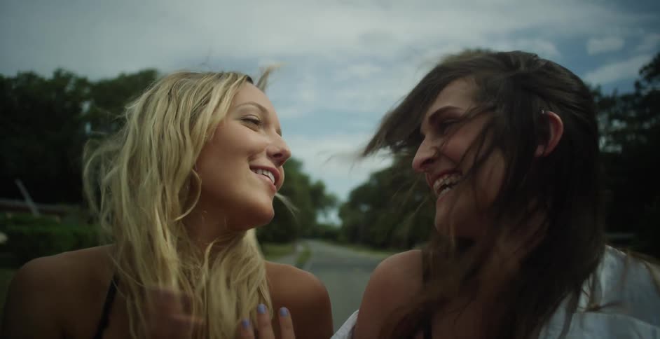 Two women laugh and talk riding down a road