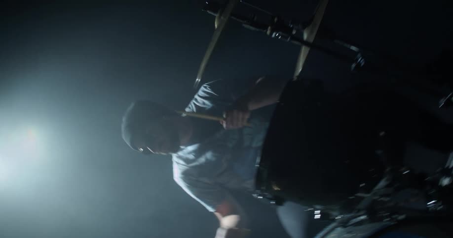 A man plays the drums in a dark room