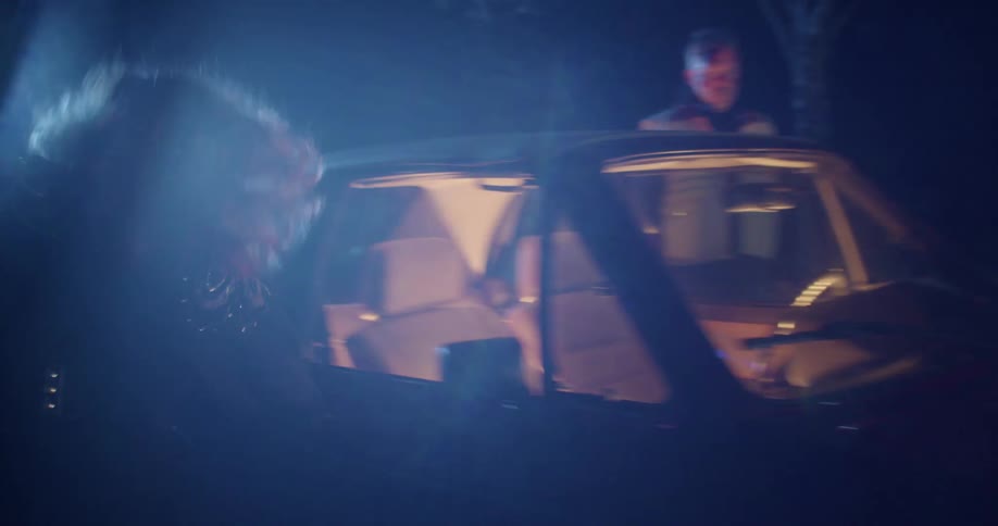 On foggy night near trees woman flees staring bruised man running around to get into car passenger seat