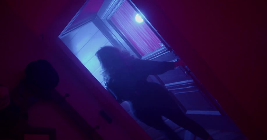Woman leaves house lit by colored lights slamming door behind her