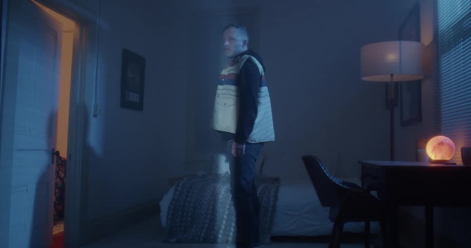 Man standing in bedroom looking toward ajar door turns as bright light turns on partly shining on him