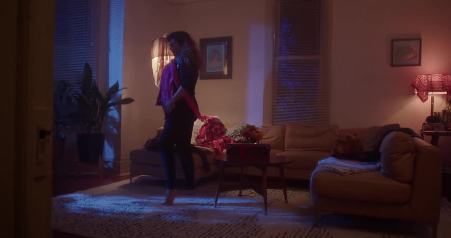 Woman dances while trying clothes on the living room at night